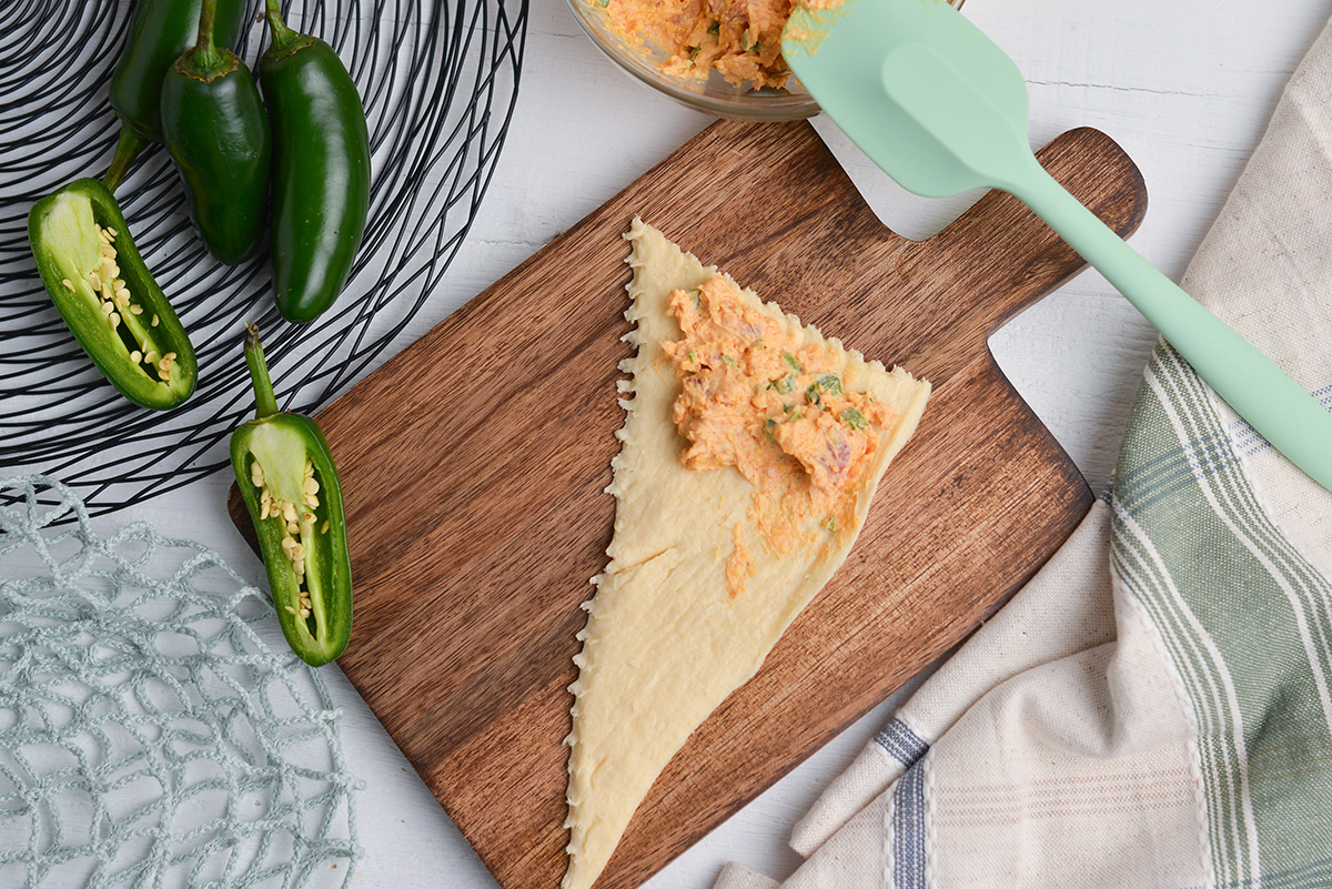 Cream cheese jalape&ntilde;o popper filling spooned onto crescent dough before rolling