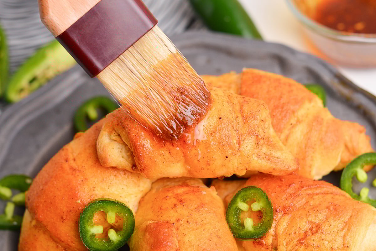 Brushing baked jalape&ntilde;o popper puffs with seasoned butter for extra flavor