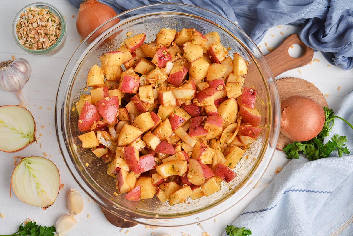 potatoes and onions in bowl with seasoning