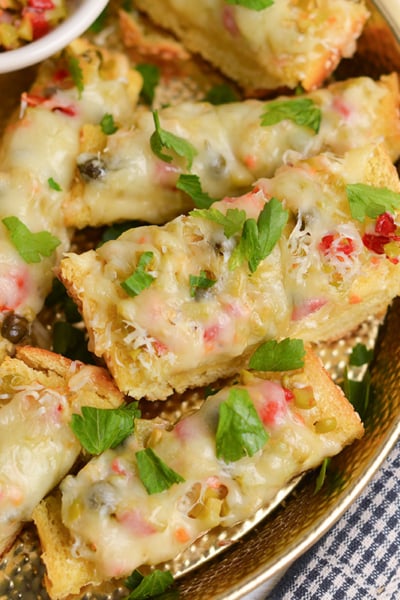 sliced olive cheese bread with melted cheese and chopped parsley