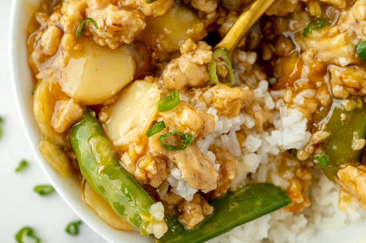 close up of ground orange chicken on fork