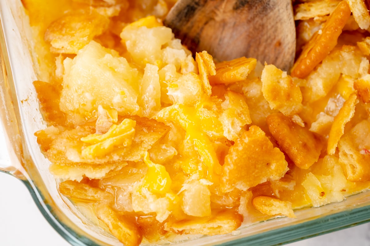 Spoonful of pineapple casserole showing cheesy pineapple filling and crisp topping