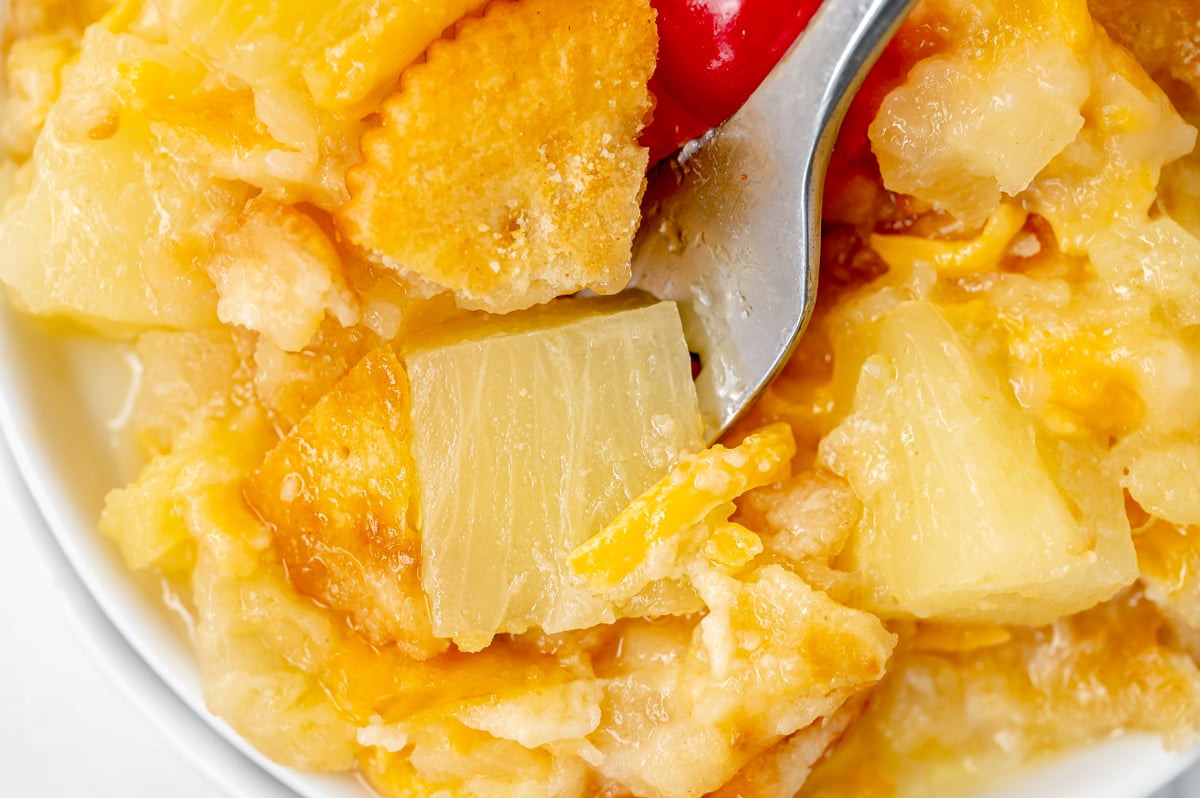 Serving of Southern pineapple casserole topped with a maraschino cherry