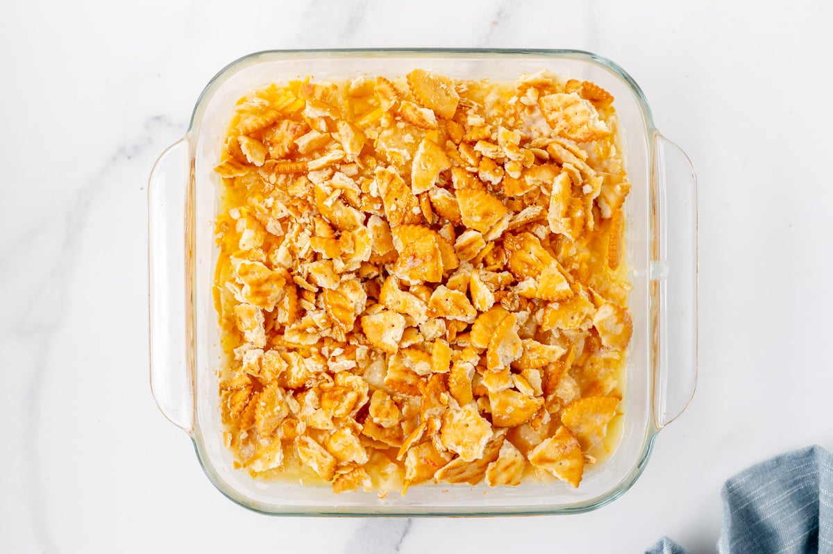 Ritz cracker topping being added to pineapple casserole before baking